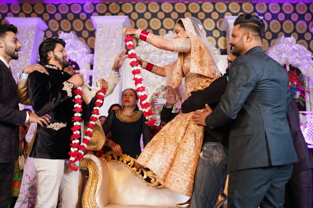 Colorful Indian wedding ceremony with bride and groom exchanging floral garlands in traditional attire.