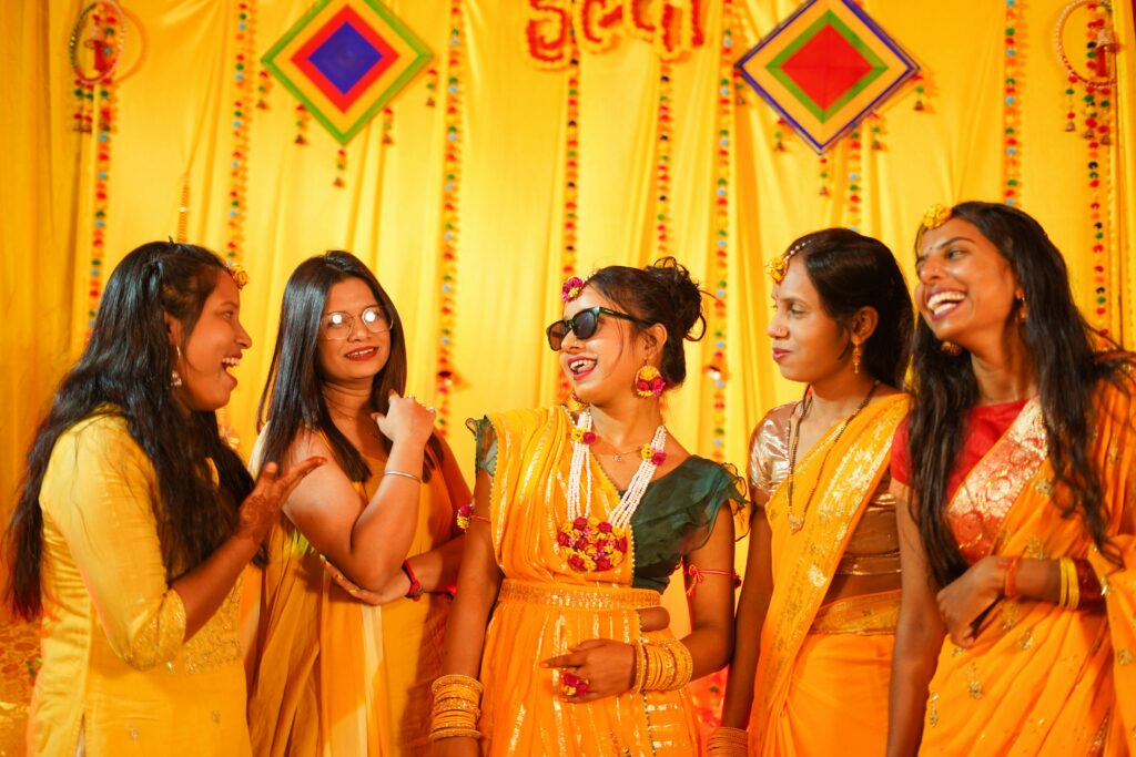 Joyful group of women celebrating a traditional Indian haldi ceremony with bright colors.